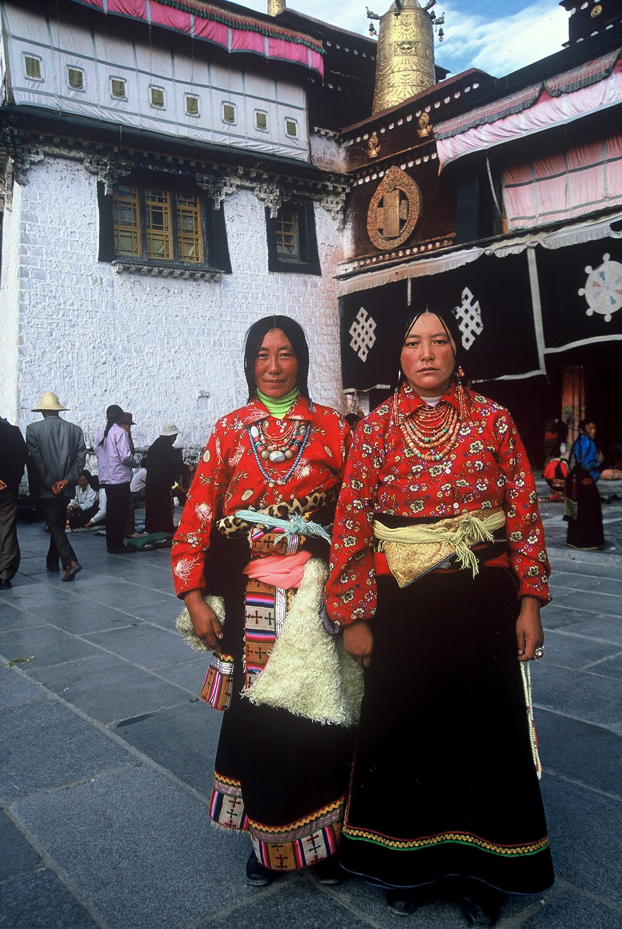 Två kvinnor i färggranna dräkter på ett torg