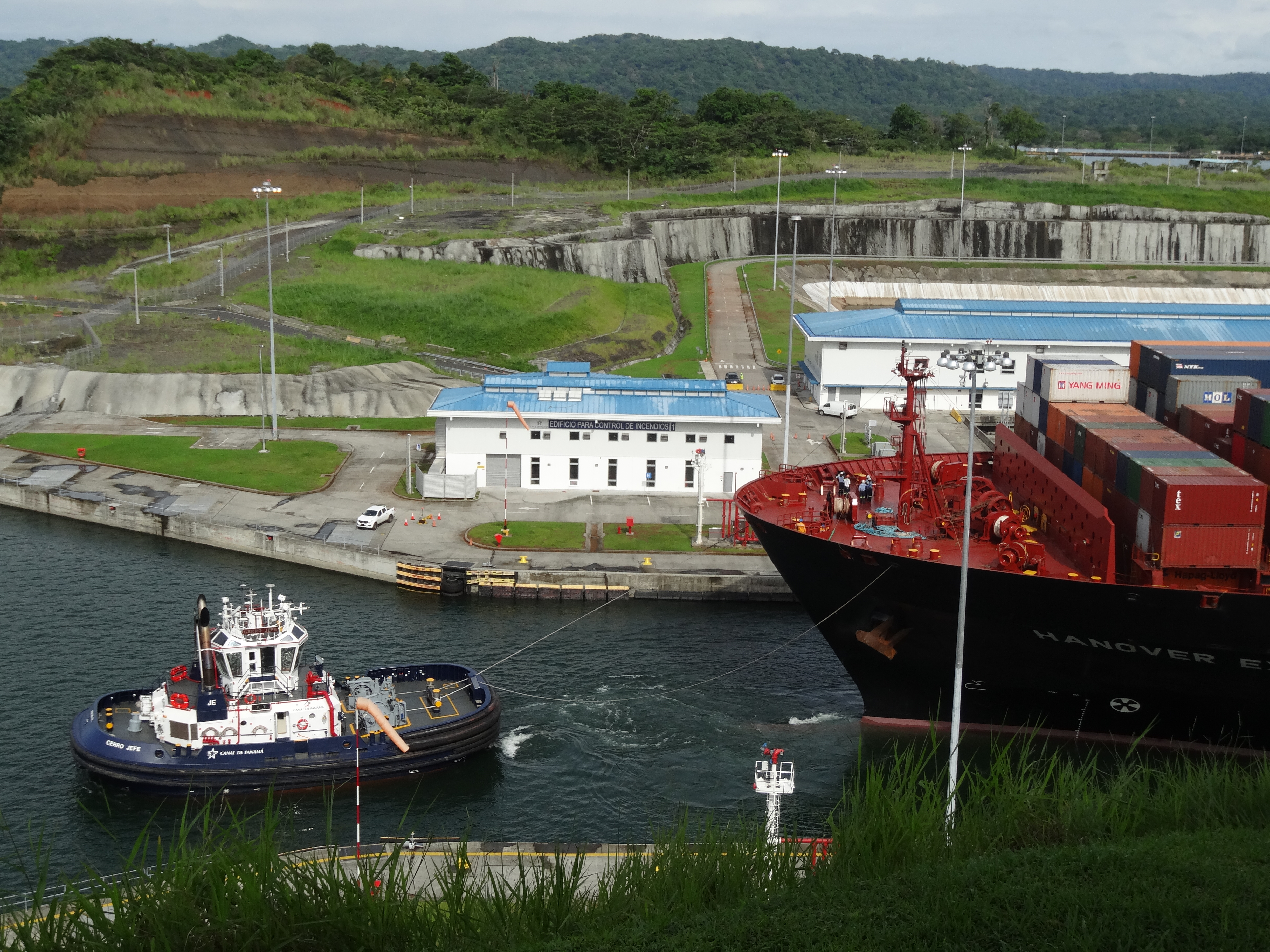 Bogseringsbåt slussar en fraktbåt genom kanal.