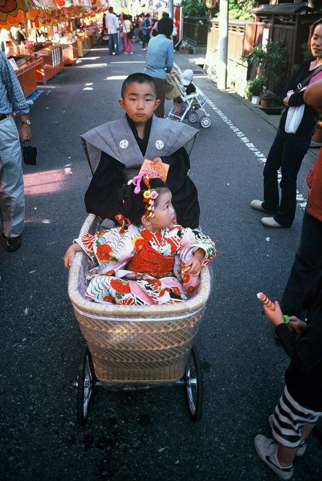 Ung kille drar en flicka i barnvagn