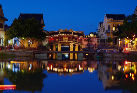 Belyst kvällsbild över gammal bro i staden Hoi An