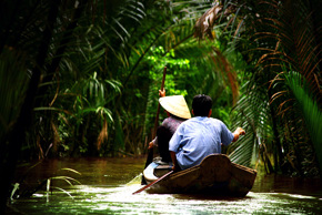 Par som paddlar i trång kanal omgärdade av växtlighet