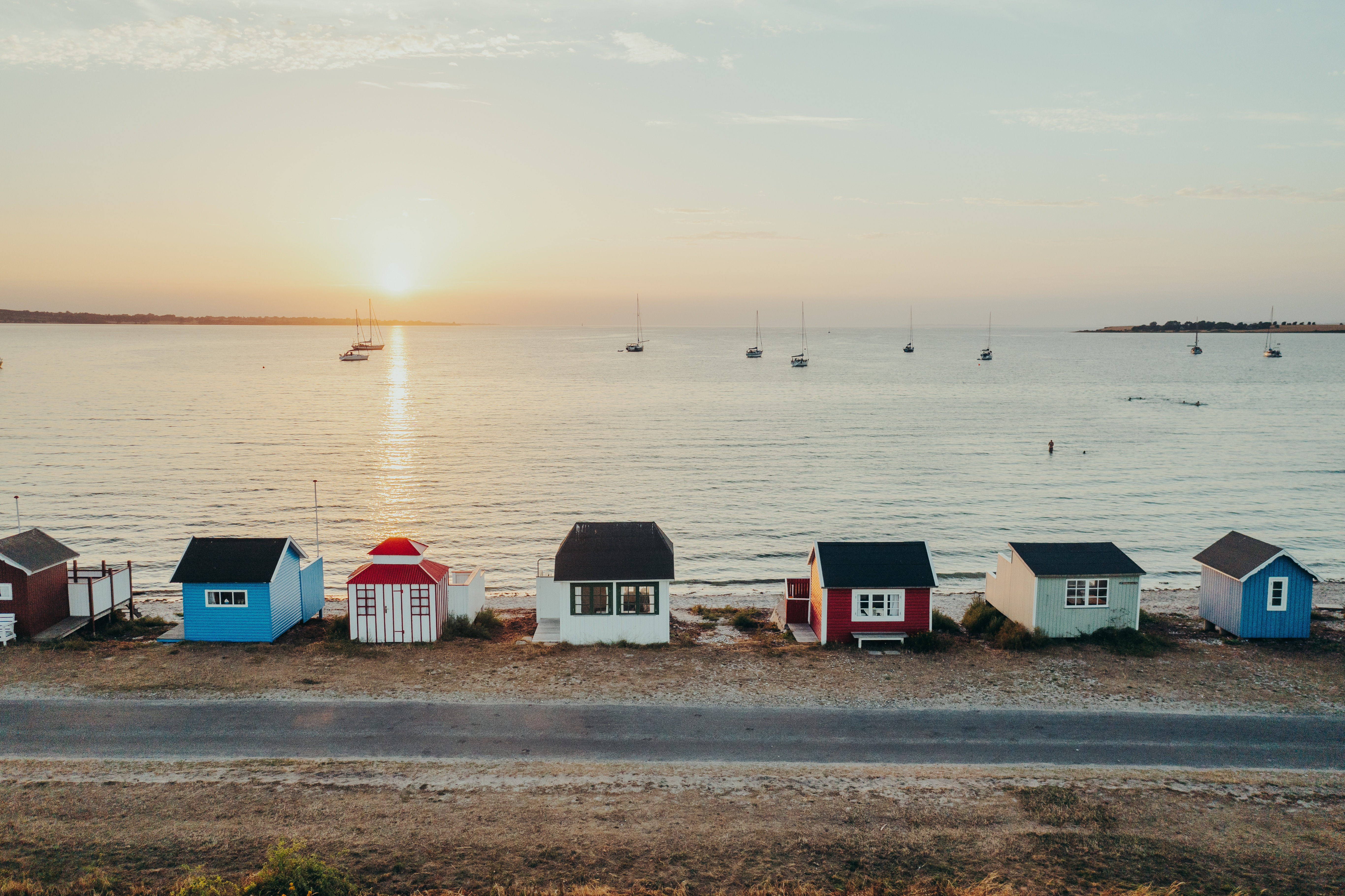 Solnedgång över färgglada badhytter vid stranden. 