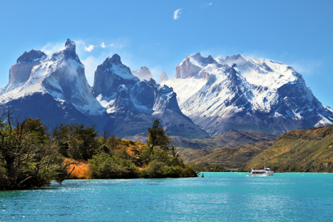 Båt som färdas på sjö och höga ber i nationalparken Torres del Paine.