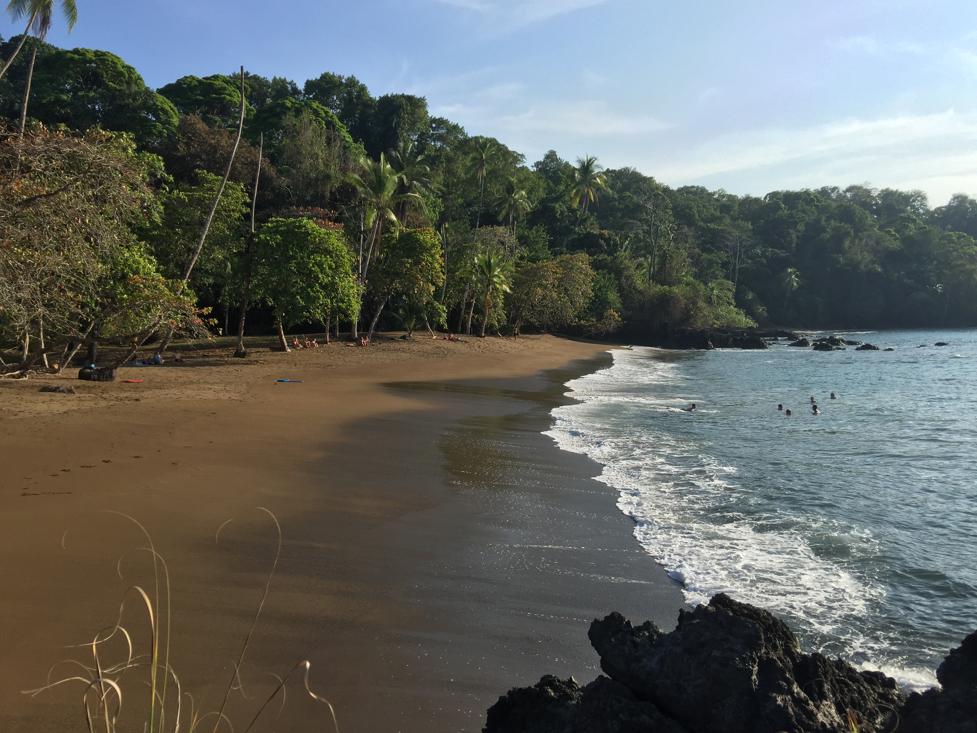 Strand och människor som badar, skymning