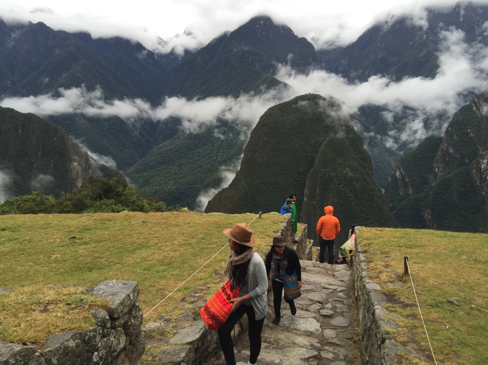 Moln över berg nära Machu Picchu och människor som går intill platåerna. 